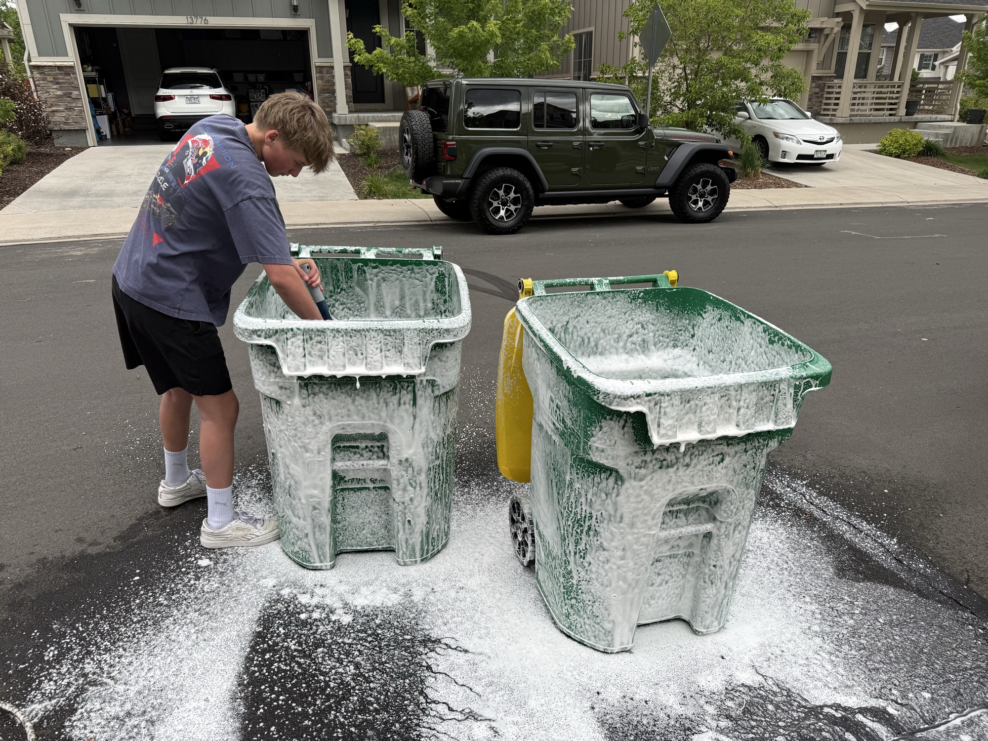 Two green trash bins covered with cleaning foam during Bin Boss service