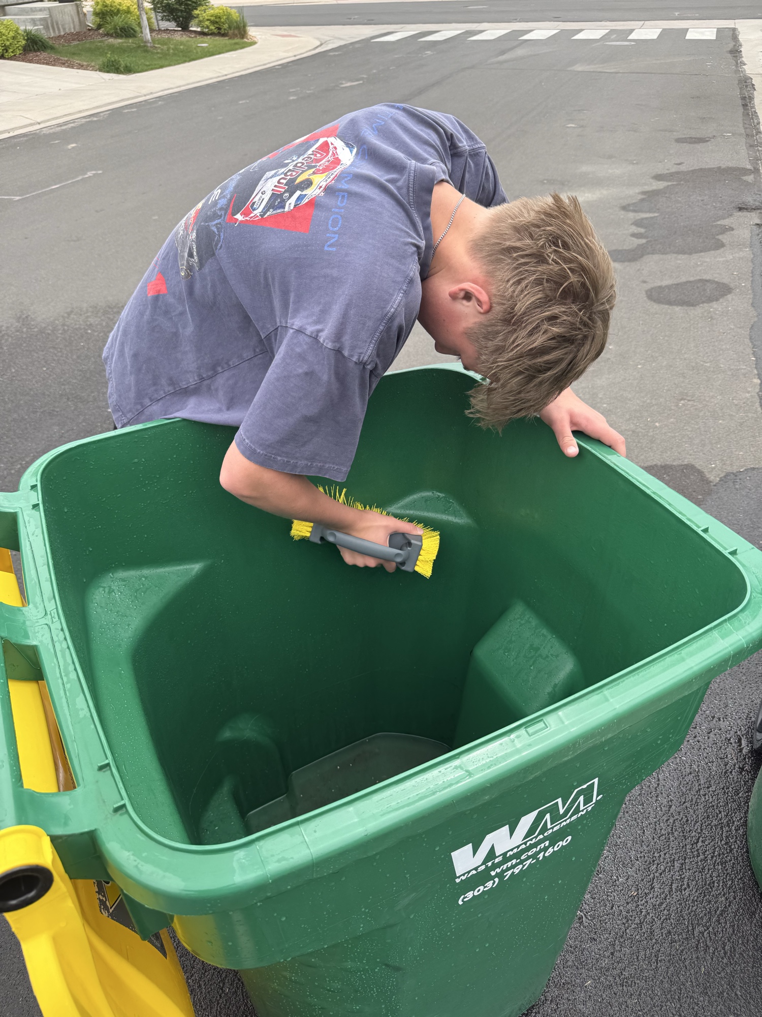 Jack scrubbing the inside wall of a green trash bin
